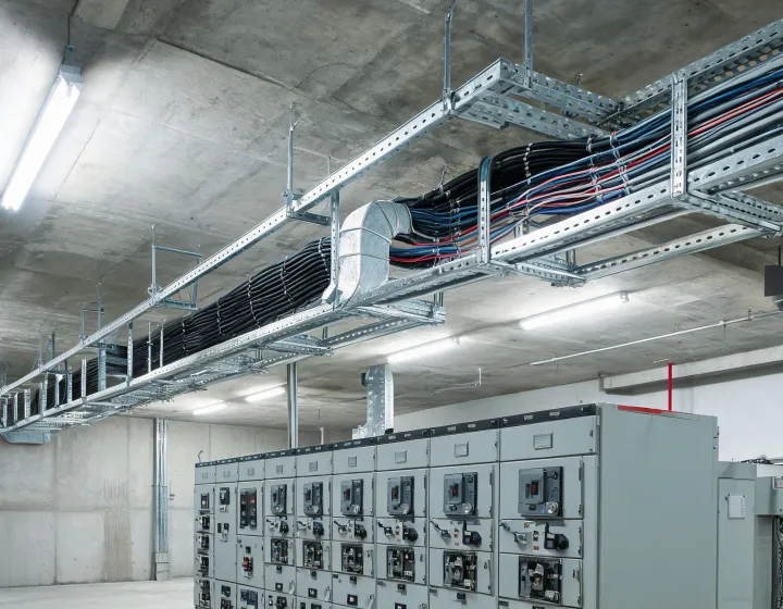 Galvanized ladder cable tray routed above industrial switchgear